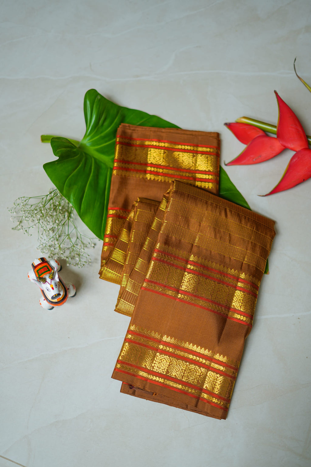 Brown Silk Saree with Copper Zari: chocolate-brown silk with a copper and gold zari border (folded)