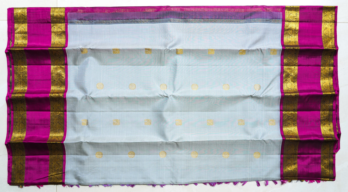 Ivory Silk Saree with Magenta Border: ivory silk with small gold butas and a magenta and gold zari border (laid flat)