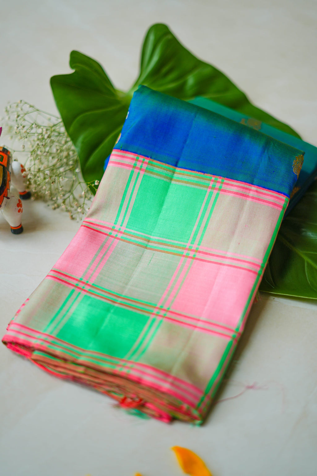 Mint & Pink Checked Silk Saree: mint-green and pink checks with gold butas and a royal-blue edge (folded)