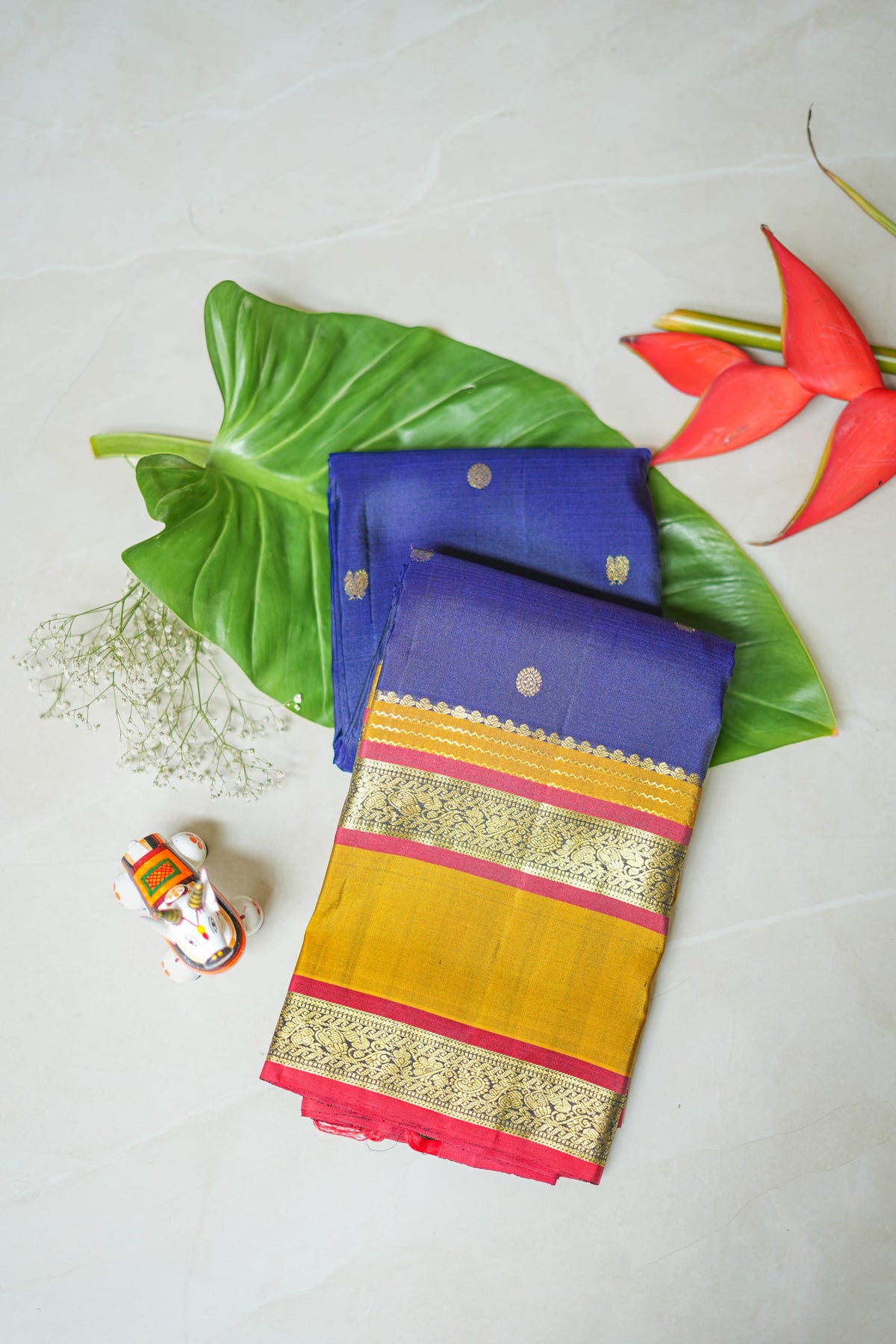 Navy Silk Saree with Mustard Border: navy silk with gold butas, a mustard and red zari border and a peach brocade pallu (folded)