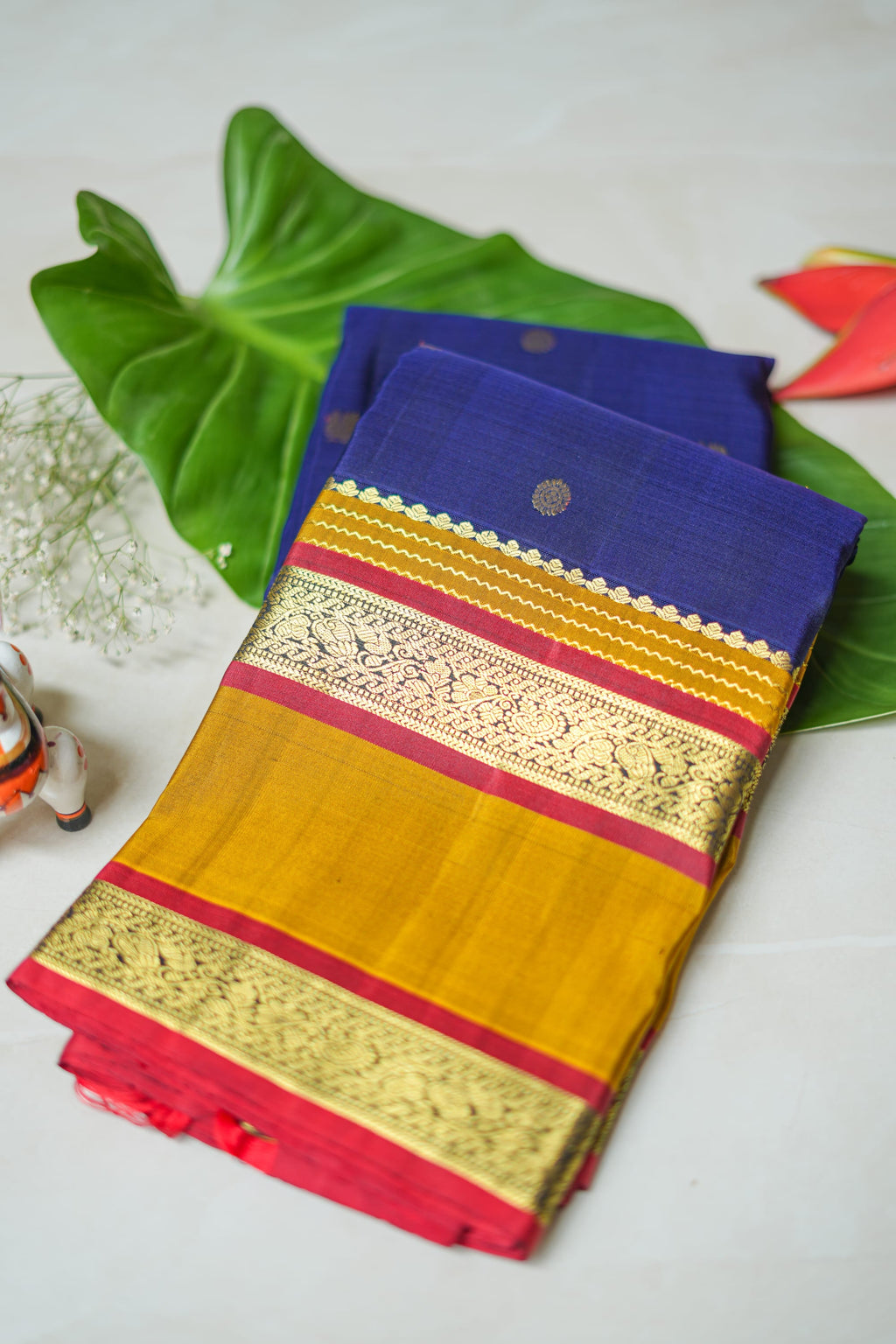 Navy Silk Saree with Mustard Border: navy silk with gold butas, a mustard and red zari border and a peach brocade pallu (folded)