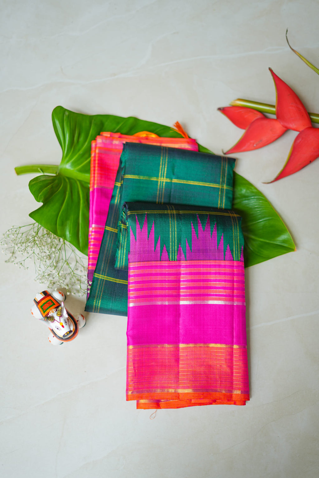 Teal Checked Silk Saree with Pink Temple Border: teal-green zari checks with a rani pink temple border and an orange edge (folded)