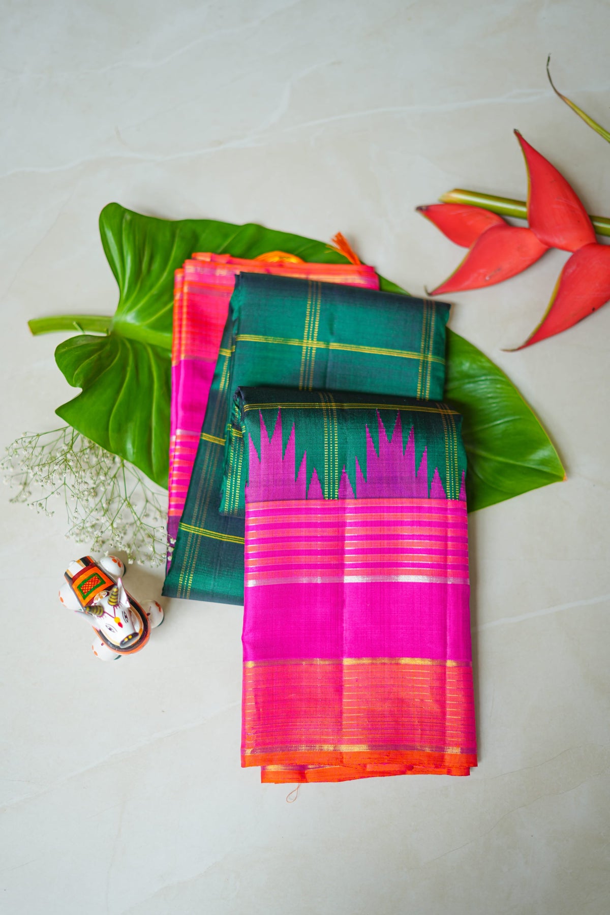 Teal Checked Silk Saree with Pink Temple Border: teal-green zari checks with a rani pink temple border and an orange edge (folded)